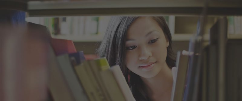 student looking through book shelf