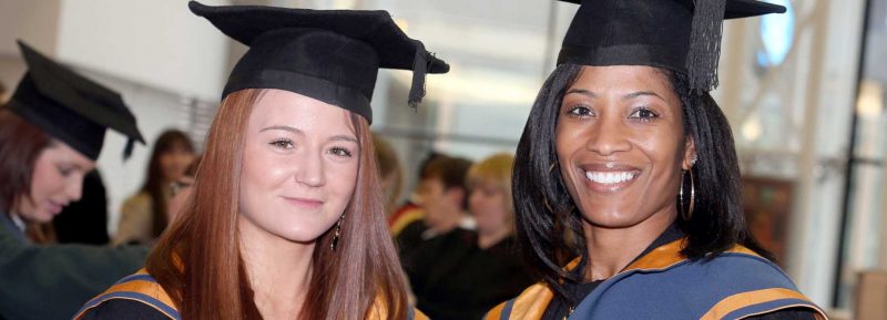 two university students in their cap and gowns
