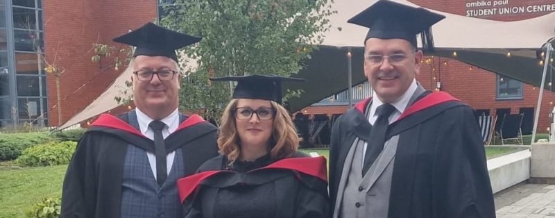 Three teachers in cap and gown graduating