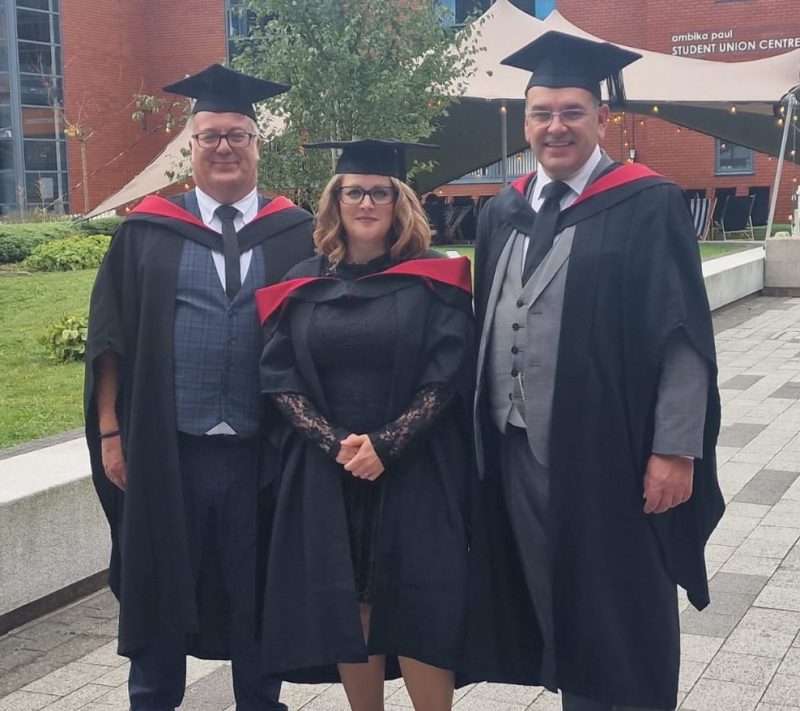 Three teachers in cap and gown graduating