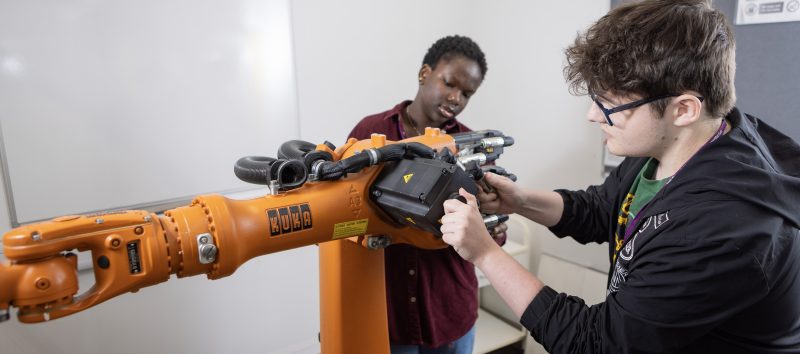 Engineering students working on robotic arm